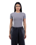 A woman modeling a fitted short-sleeve crewneck top in light gray, paired with dark charcoal sweatpants, against a plain white background. [model:2]