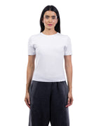 A woman modeling a plain white short-sleeve crewneck t-shirt paired with dark charcoal gray wide-leg pants, shot against a seamless white background. [model:2]