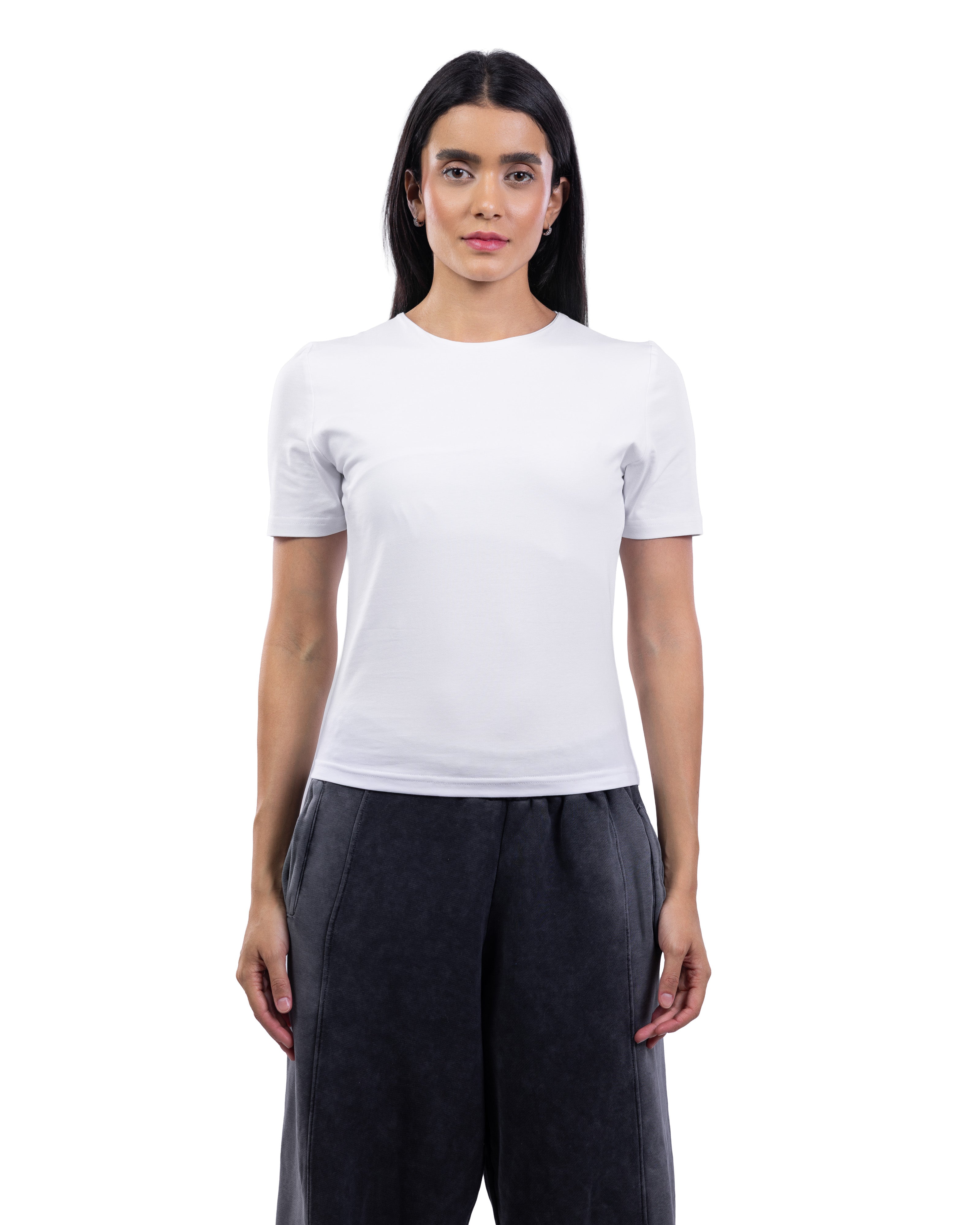 A woman modeling a plain white short-sleeve crewneck t-shirt paired with dark charcoal gray wide-leg pants, shot against a seamless white background.