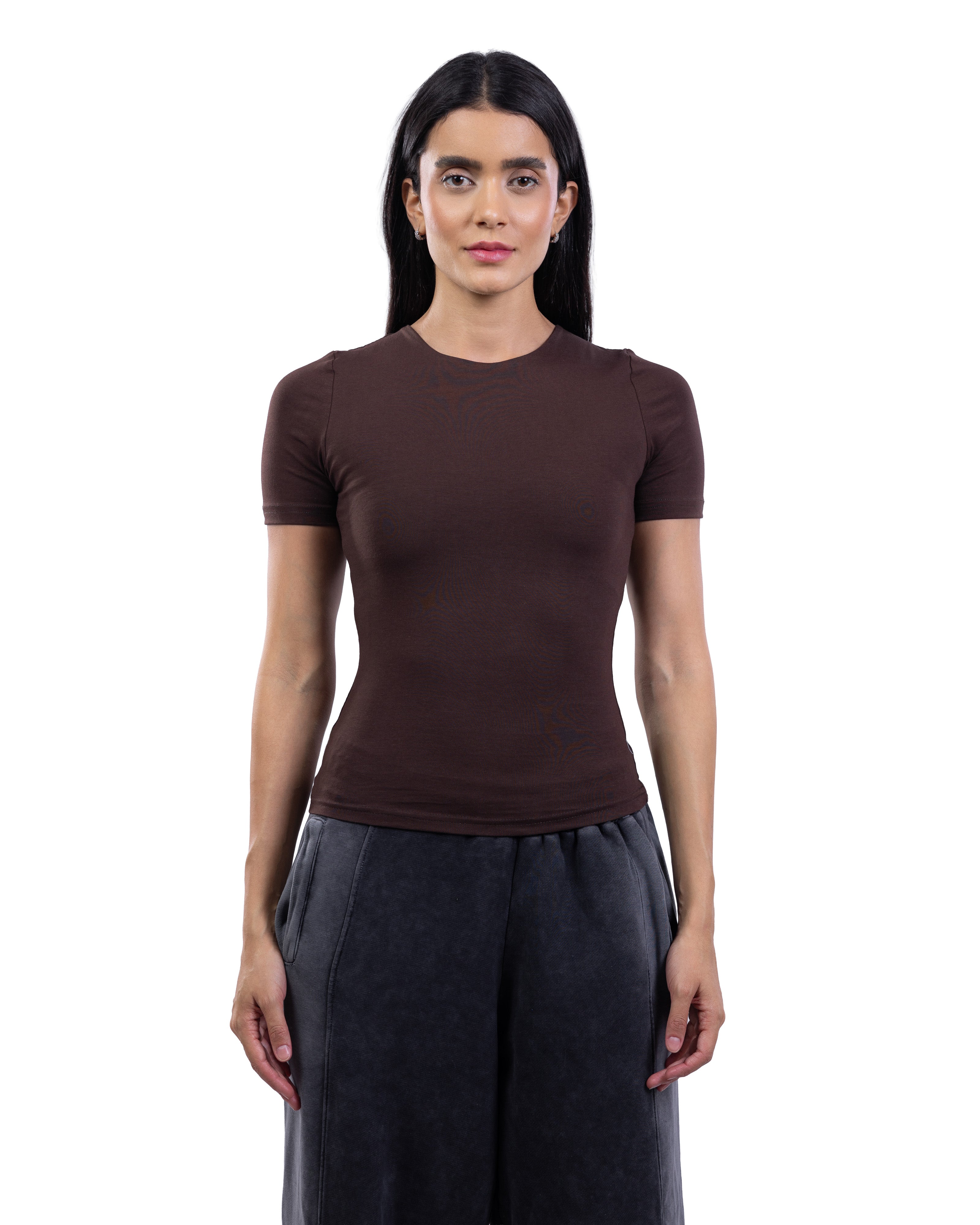 A woman modeling a fitted short-sleeve crewneck top in dark brown, paired with dark gray wide-leg pants, against a plain white background.