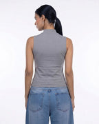 A woman shown from the back wearing a fitted sleeveless mock-neck top in heather gray and blue jeans, photographed against a plain white studio background. [model:1]