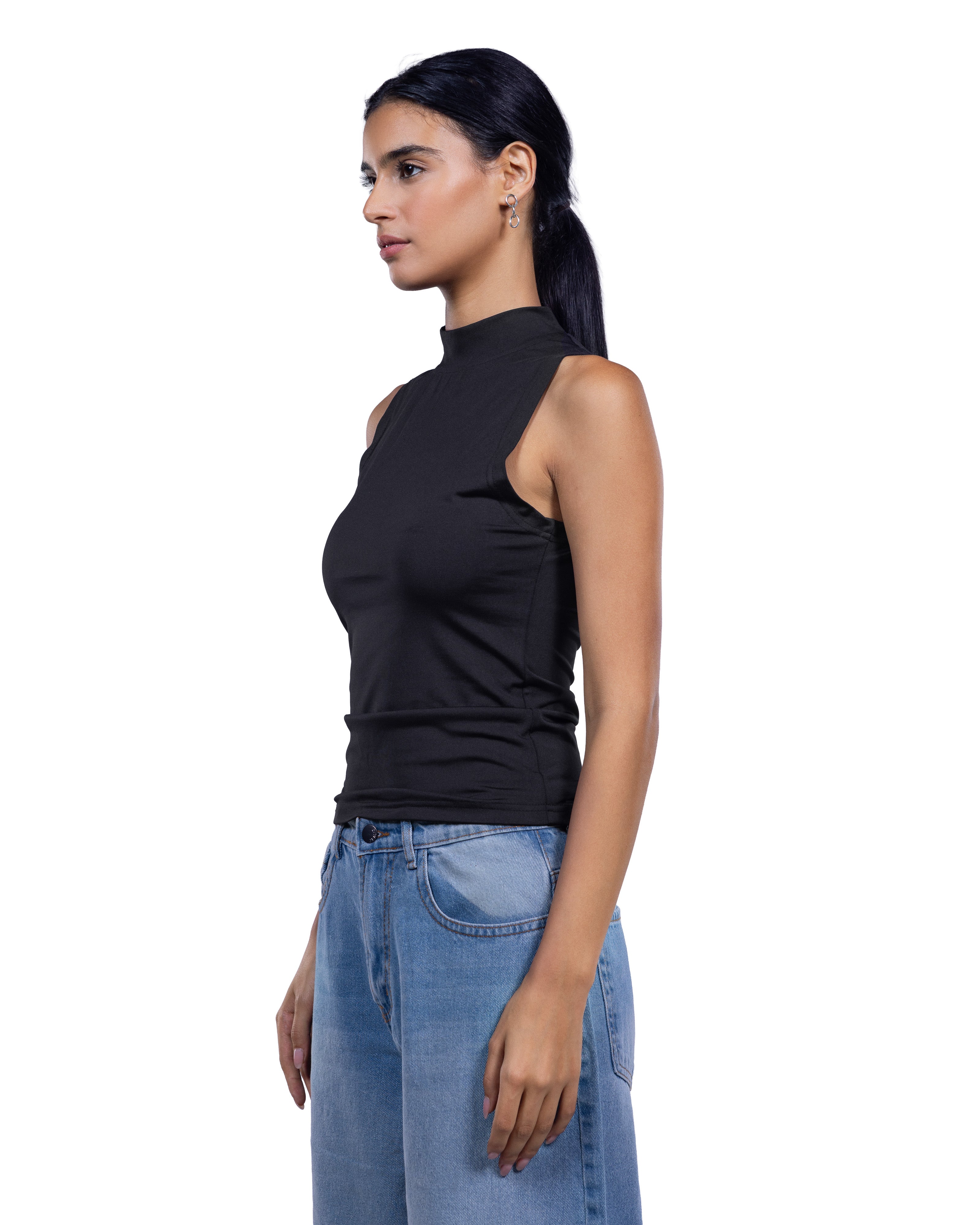 A woman shown in side profile wearing a fitted sleeveless black mock-neck top and light blue jeans against a plain white studio background.