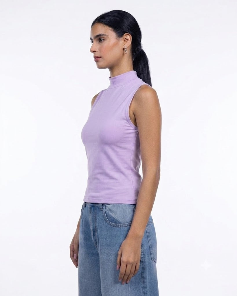 A woman in profile wearing a sleeveless lavender mock neck top and blue jeans, standing against a plain white studio background.