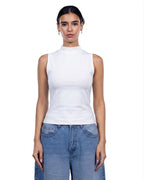 A woman modeling a white sleeveless mock neck top paired with light blue jeans against a plain white background. [model:1]
