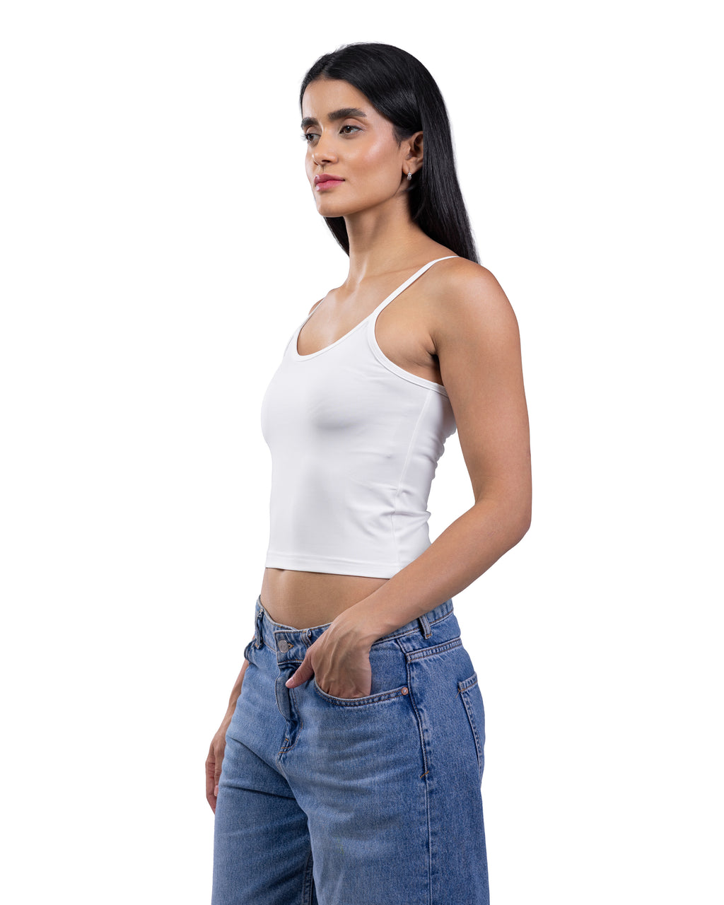 A woman wearing a fitted white spaghetti-strap crop tank top and blue jeans, shown in side profile against a plain white background.
