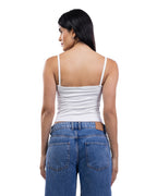 A woman shown from the back wearing a white spaghetti-strap camisole top and blue jeans against a plain white background.