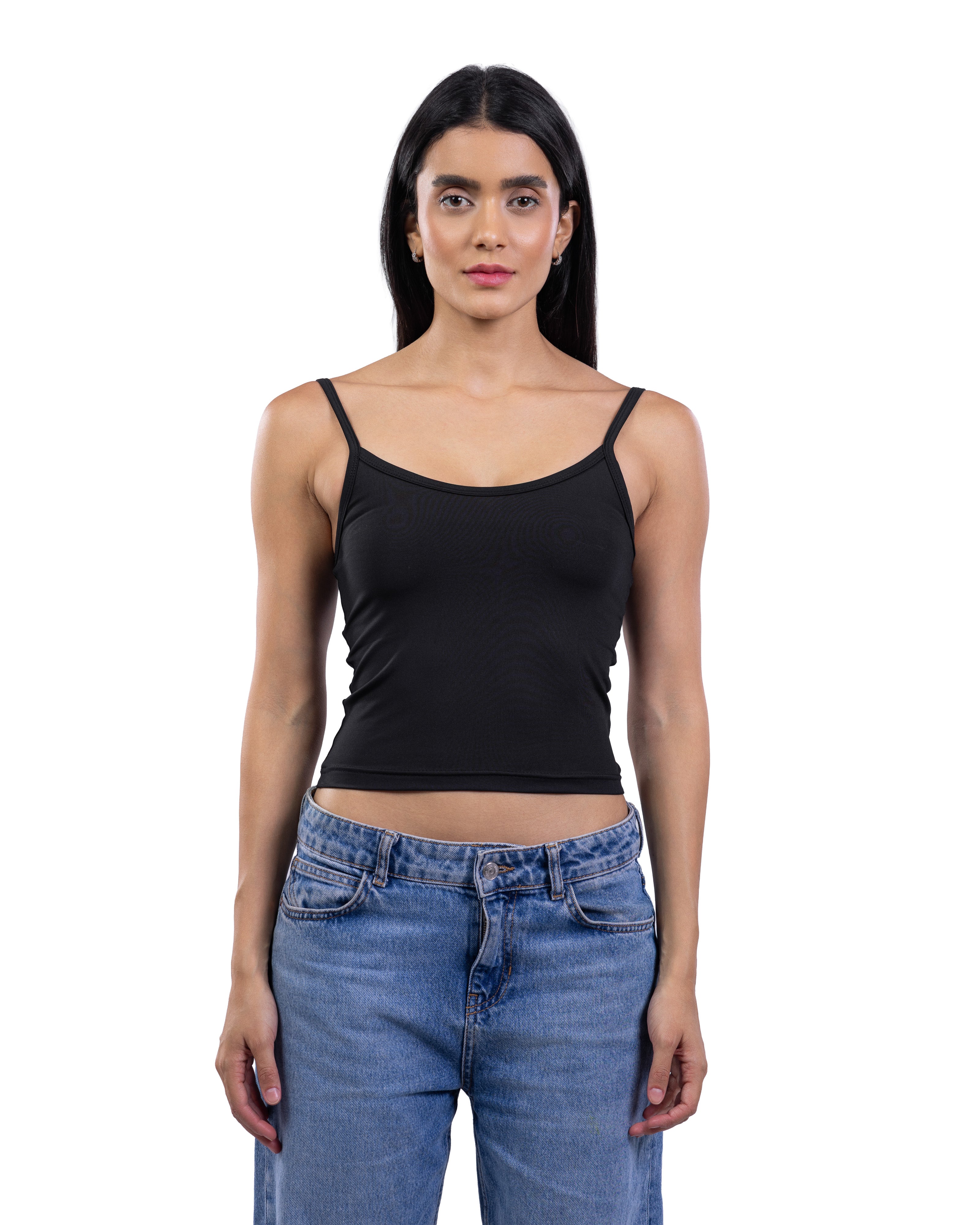 A woman modeling a black spaghetti-strap tank top paired with blue jeans, shot against a solid white background.