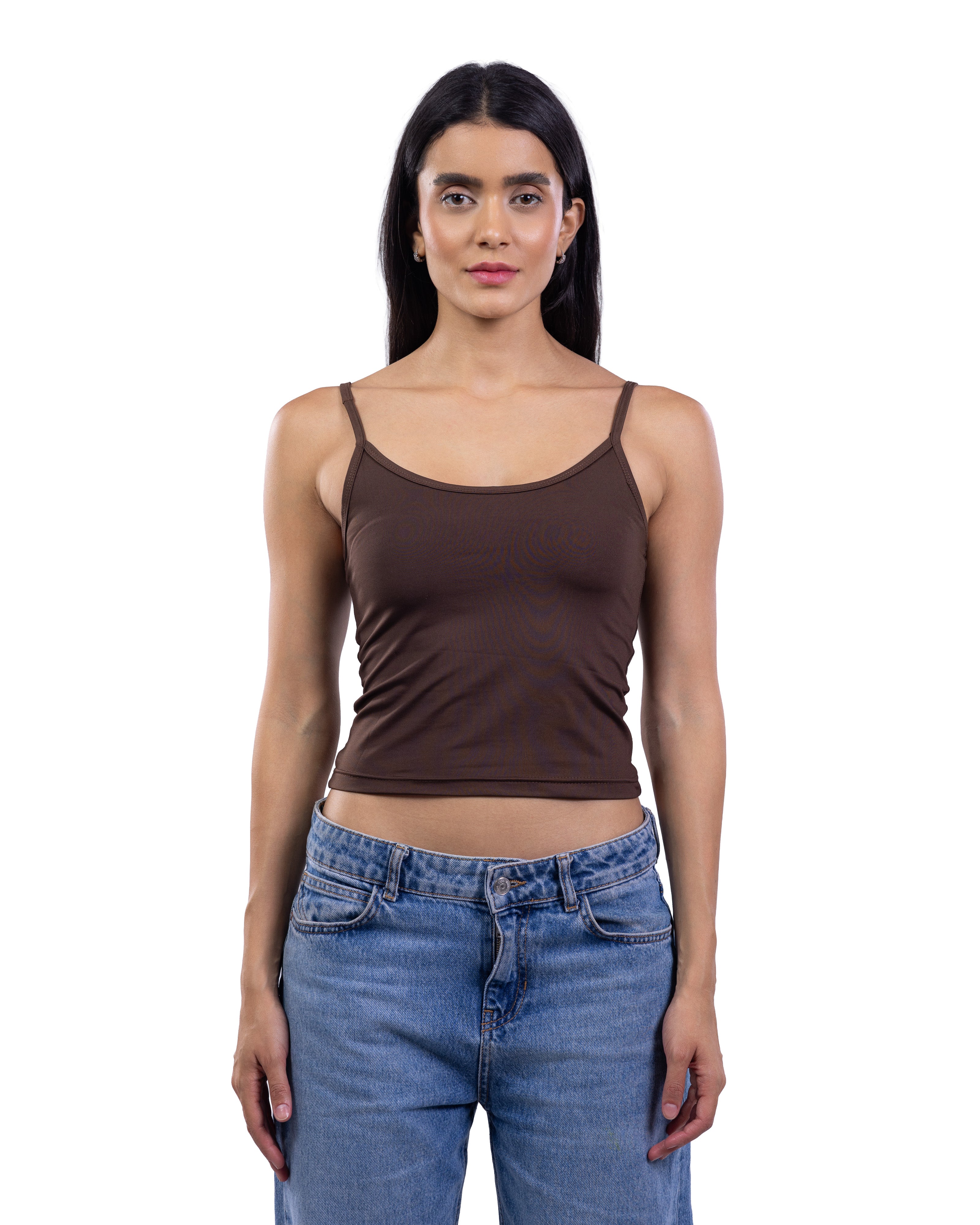 A woman modeling a dark brown ribbed spaghetti-strap tank top paired with blue jeans, shot against a solid white background.