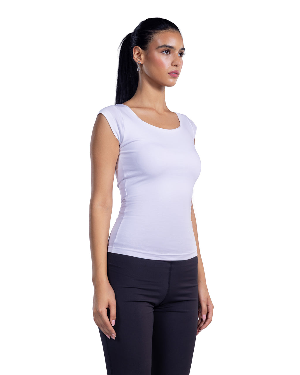 A woman with dark hair in a ponytail is shown from the side, wearing a fitted white scoop-neck sleeveless top and black leggings against a plain white background.