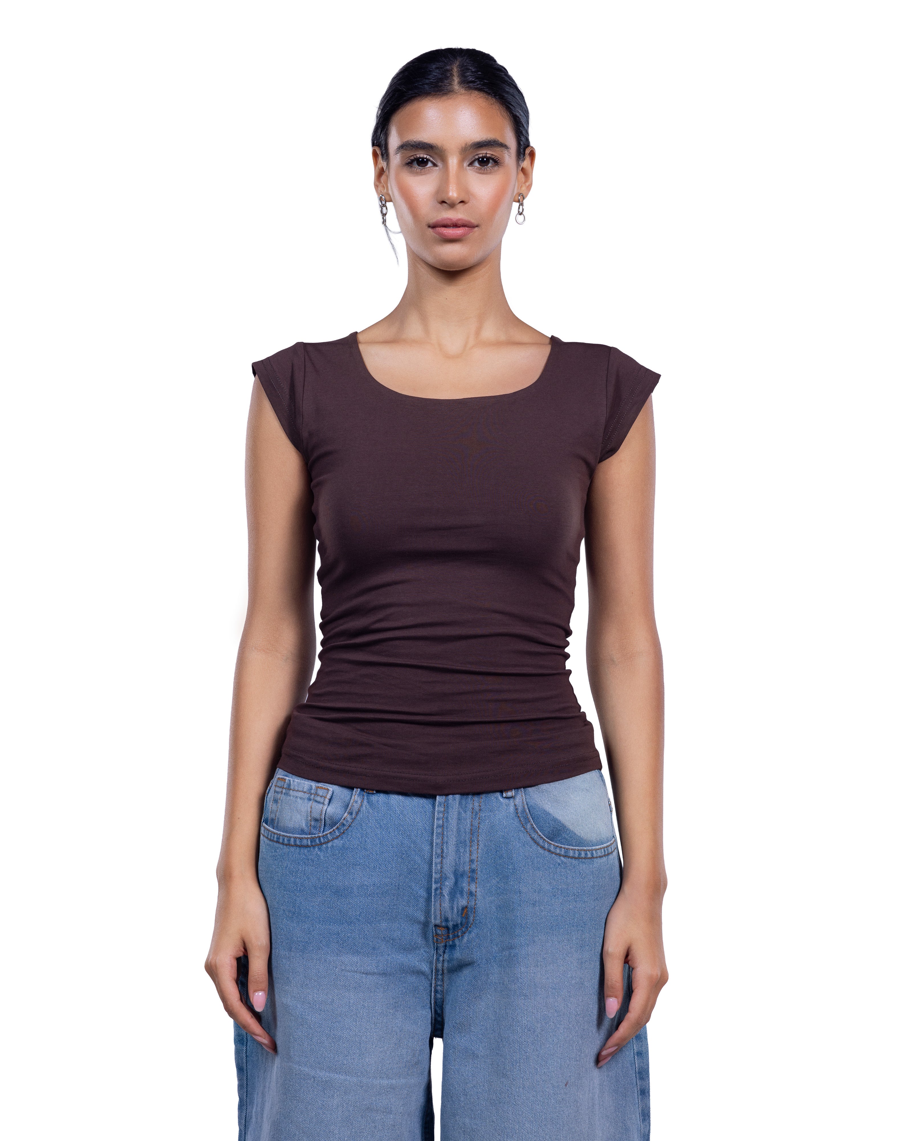 A woman modeling a dark brown scoop-neck ribbed t-shirt with cap sleeves, paired with light blue jeans, against a plain white background.
