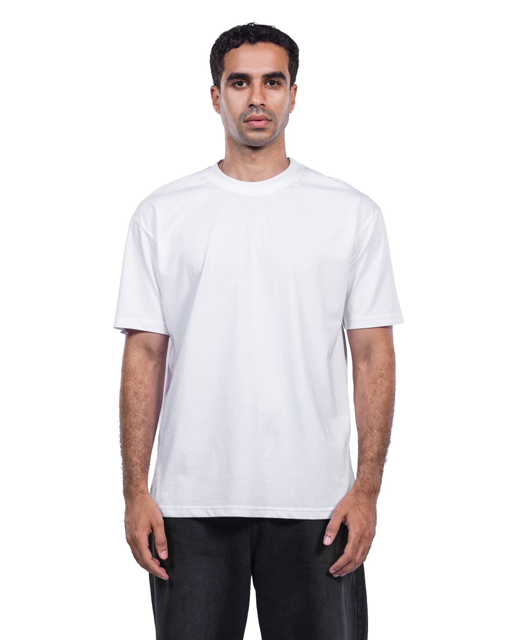 A man wearing a plain white short-sleeve crewneck t-shirt and black pants, standing against a solid white background.