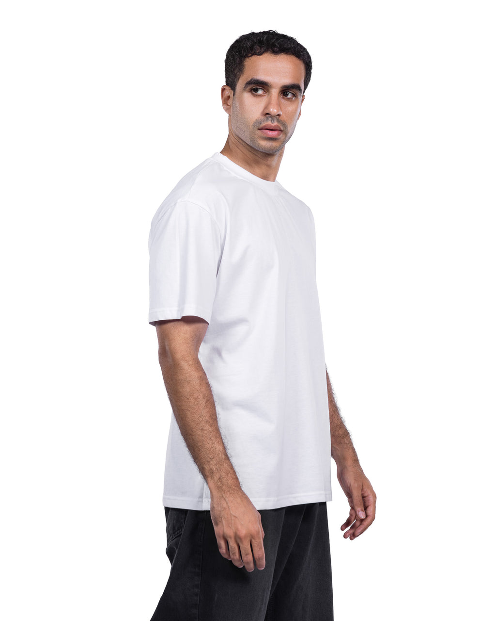 A man wearing a plain white short-sleeve crewneck t-shirt and black pants, shown from a side profile against a solid white background.