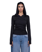A model wearing a black long-sleeve ruched top with a draped neckline and matching black hood, paired with light blue jeans, against a plain white background. [model:1]