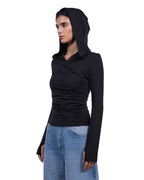 A woman wearing a black long-sleeve ruched hooded top and light blue jeans, shown in profile against a plain white background. [model:1]