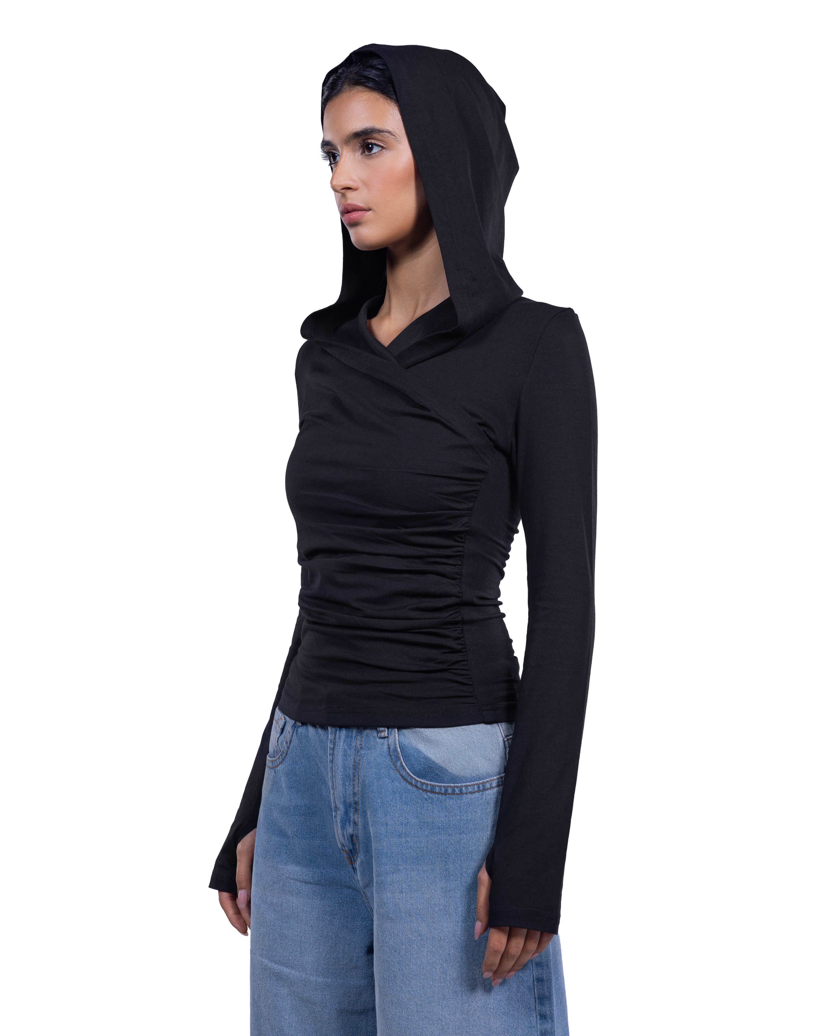 A woman wearing a black long-sleeve ruched hooded top and light blue jeans, shown in profile against a plain white background.