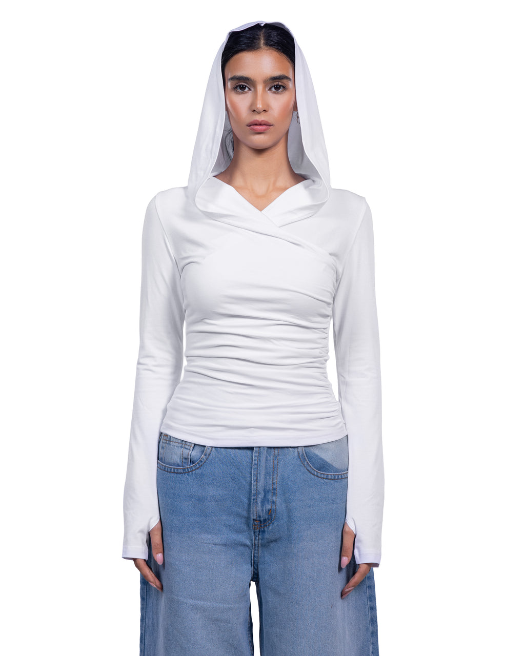 A model wearing a white long-sleeve wrap-style top with a draped hood, paired with light blue jeans, against a plain white background.