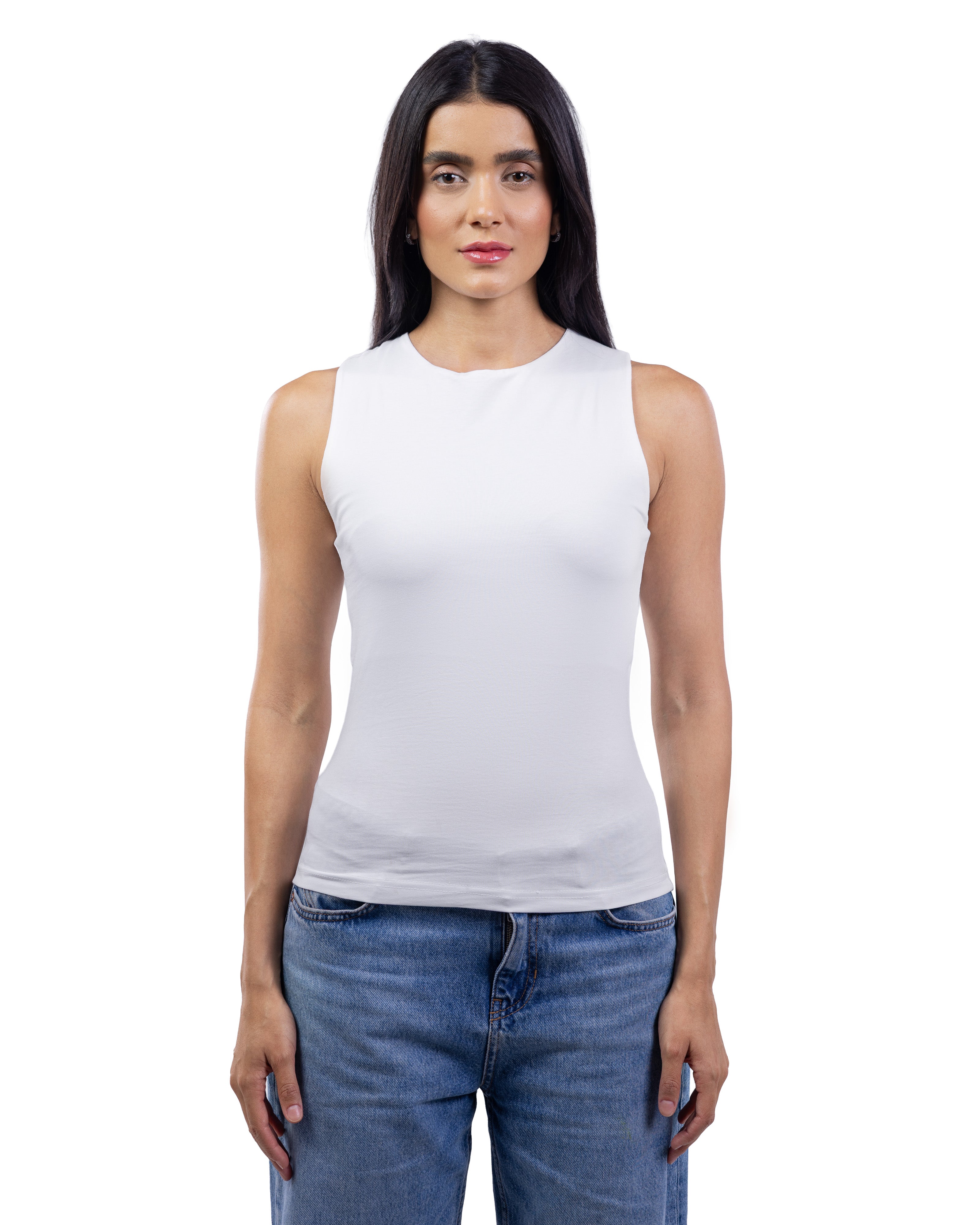 A woman modeling a white sleeveless crew-neck tank top paired with blue jeans, shot against a solid white background.