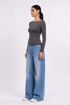 A woman modeling a dark gray long-sleeve top and wide-leg light blue jeans against a plain white studio background. [model:1]