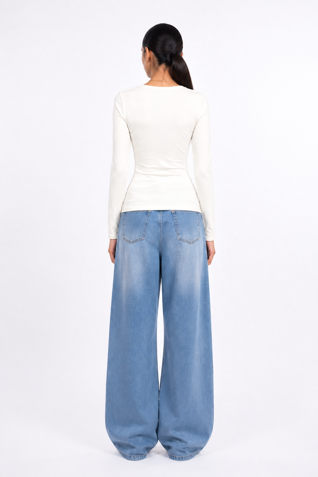 A model shown from the back wearing a fitted off-white long-sleeve top and wide-leg light blue denim jeans against a plain white studio background.